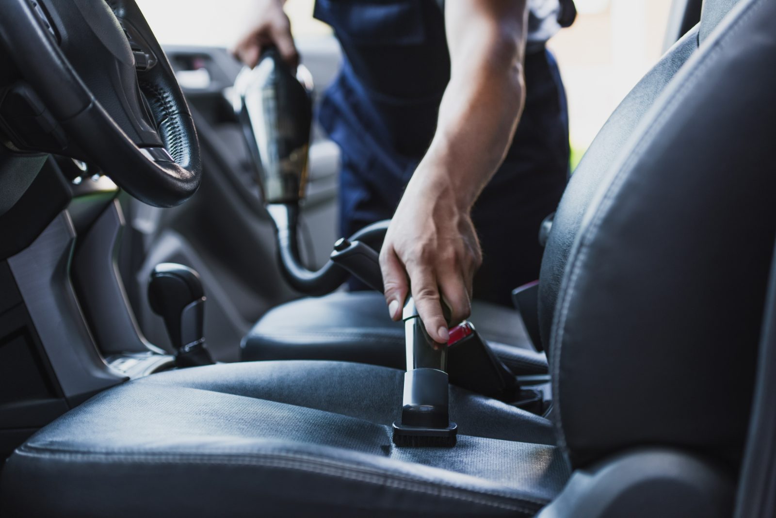 Person fastening seatbelt in car interior with steering wheel visible